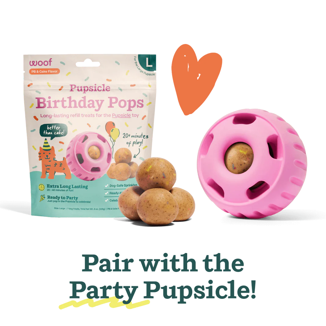 Pink Pupsicle toy dispenser with a brown treat ball and Birthday Pops package