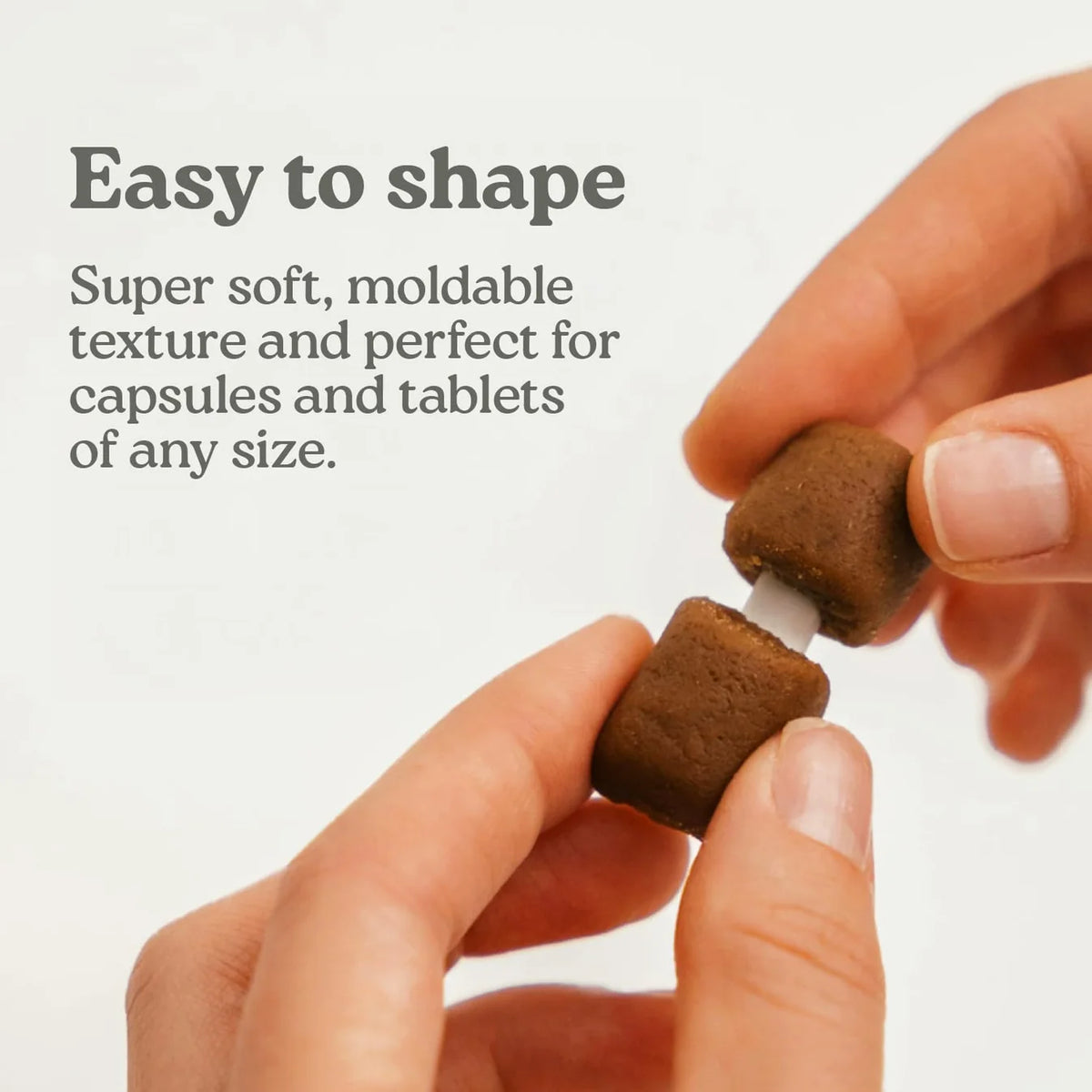 Brown pill-hiding treat being molded in fingers for pills or tablets