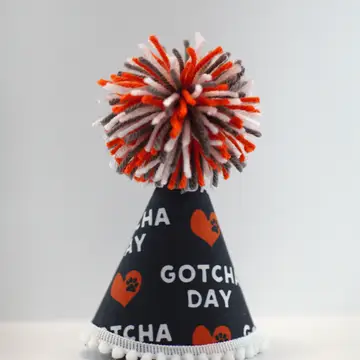 Dark cone party hat with striped orange/white pom-pom and “Gotcha Day” print