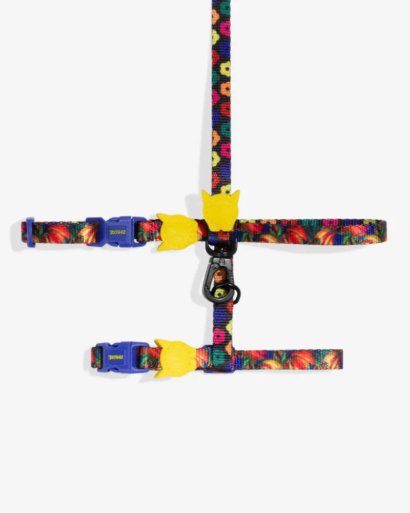 Cat harness with colorful pattern and yellow cat-face clip, adjustable straps.